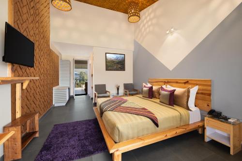a bedroom with a large bed and a tv at juSTa Lazy Haven Corbett, Uttarakhand in Rāmnagar