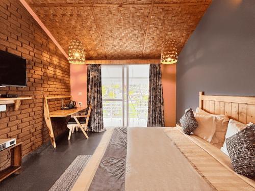 a bedroom with a bed and a desk with a television at juSTa Lazy Haven Corbett, Uttarakhand in Rāmnagar