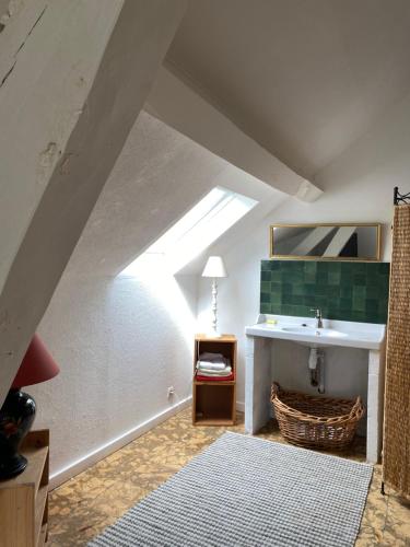 La salle de bains mansardée est pourvue d'un lavabo et d'un miroir. dans l'établissement La Clémendière, un paradis caché, à Chailly-en-Gâtinais