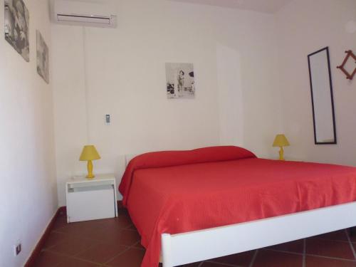 a bedroom with a red bed and a white wall at Residence La Bricola Sestante 26 in I Casoni