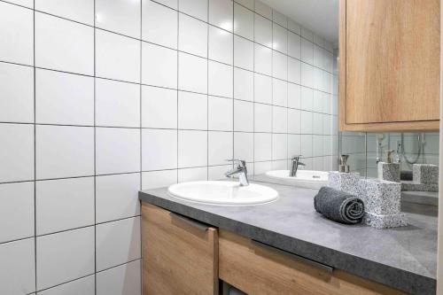 La salle de bains est pourvue de 2 lavabos et de murs carrelés blancs. dans l'établissement Le Monnet, à Annecy