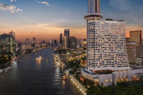 a tall building next to a river in a city at Millennium Hilton Bangkok in Bangkok
