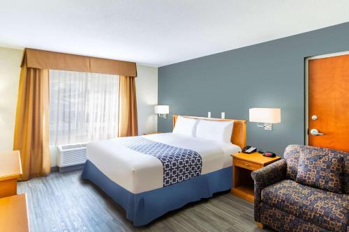 a hotel room with a bed and a chair at Econo Lodge Inn & Suites University in Calgary