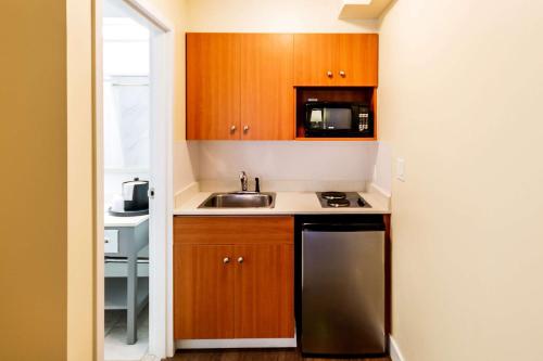 a small kitchen with wooden cabinets and a sink at Econo Lodge Inn & Suites University in Calgary
