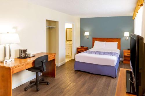 a hotel room with a bed and a desk and a computer at Econo Lodge Inn & Suites University in Calgary