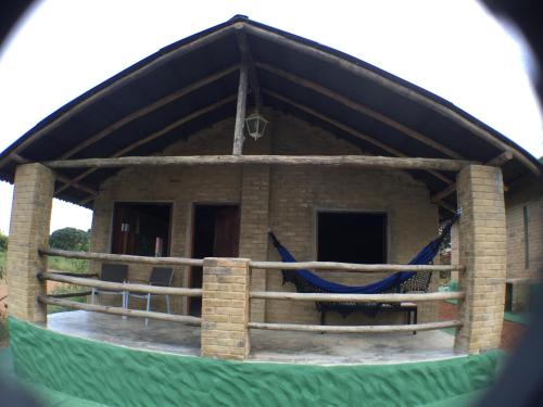 a house with a blue hammock in front of it at Pousada Morro da Baleia in Alto Paraíso de Goiás