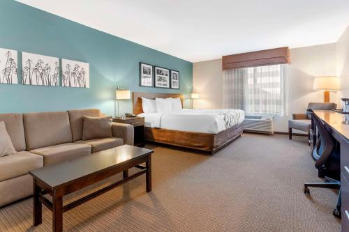 a hotel room with a bed and a couch at Sleep Inn & Suites Cumberland in Cumberland