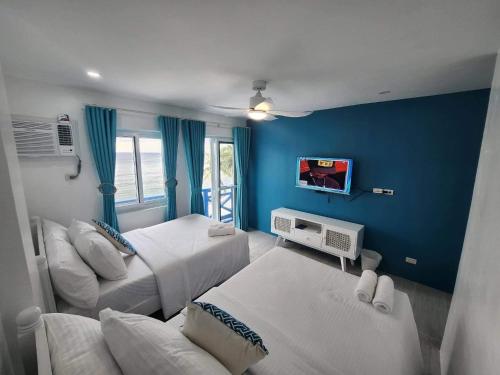 a bedroom with two beds and a blue wall at OIA by Seascape in Bauan