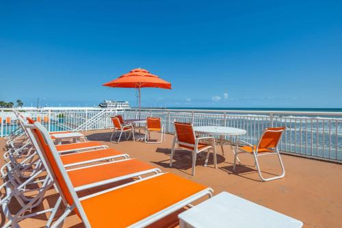 a deck with chairs and tables and an umbrella at Comfort Inn & Suites Daytona Beach Oceanfront in Daytona Beach