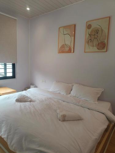 a bedroom with a white bed with two pictures on the wall at The Pampines Villa, Mount Kinabalu in Ranau