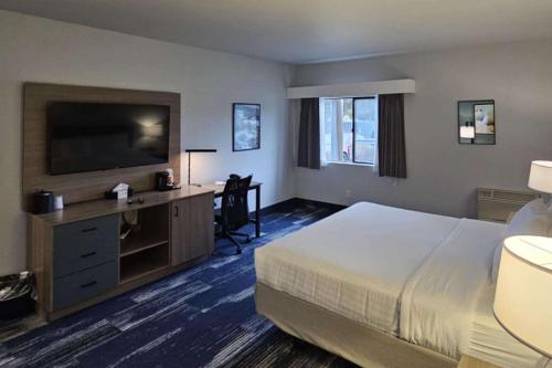 a hotel room with a bed and a flat screen tv at Edgewater Inn and Suites, an Ascend Collection Hotel in Coos Bay
