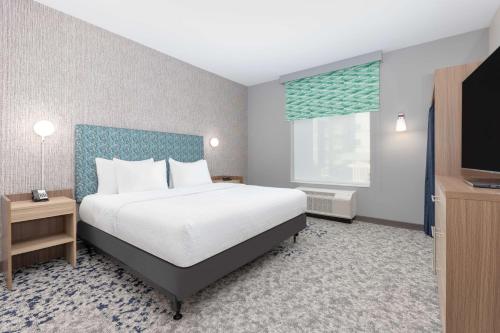a hotel room with a bed and a flat screen tv at Home2 Suites By Hilton Dallas I-30 Cockrell Hill in Dallas
