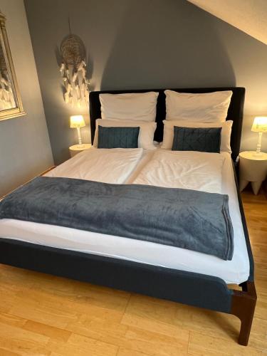 a large bed in a bedroom with two lamps at Lovely guest suite in country villa near Cologne in Kerpen