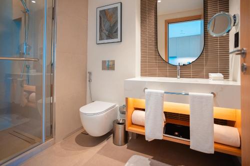 a bathroom with a toilet and a sink and a mirror at Exclusive Residences at Address Marassi Vista in Amwaj Island