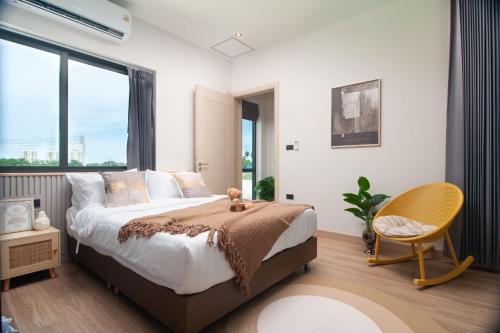 Un dormitorio con una cama y una silla y una ventana. en Nacha Pool Villa Cha-am, en Cha Am