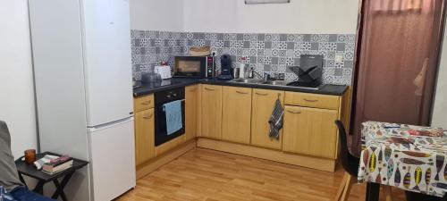 une cuisine avec des armoires en bois et un réfrigérateur blanc dans l'établissement T2 au cœur de La Ciotat, à La Ciotat