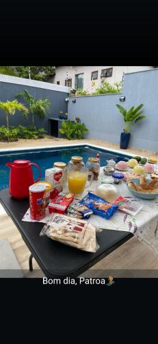 a table with food and drinks on it next to a pool at Suíte tripla com vista piscina em casa familiar de luxo em Itaipu in Niterói