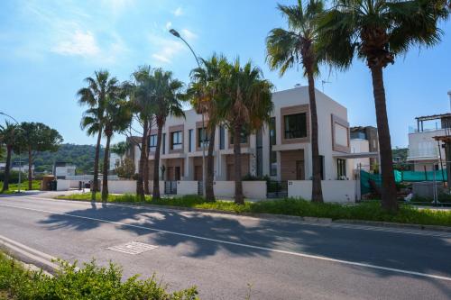 a building with palm trees on the side of a street at WealthyStays 2BR Retreat , 5Min Walk to Beach in Protaras