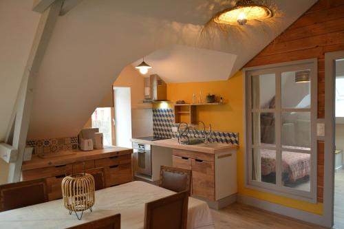 une cuisine avec une table à manger et une cuisine aux murs jaunes dans l'établissement Appartement des Cigalous, à Épinal