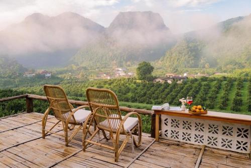 duas cadeiras num deque com vista para as montanhas em อาข่า พามิโอ้ em Ban Pha Mi