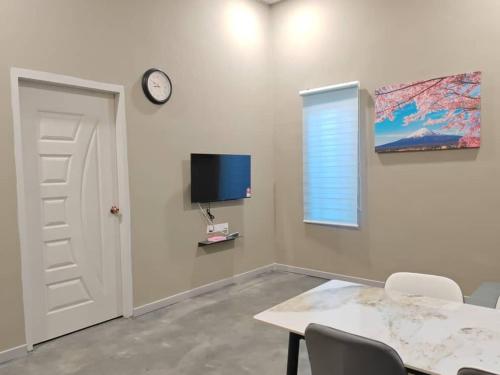 a dining room with a table and a clock on a wall at PSH Homestay in Pendang