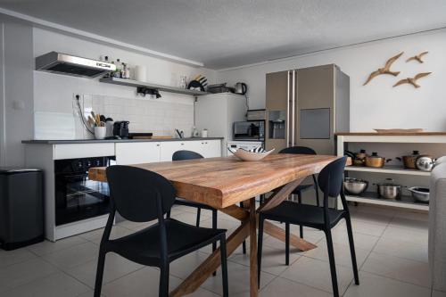une cuisine avec une table en bois et des chaises noires dans l'établissement Le Ponton et son spa, à Saint-Mandrier-sur-Mer