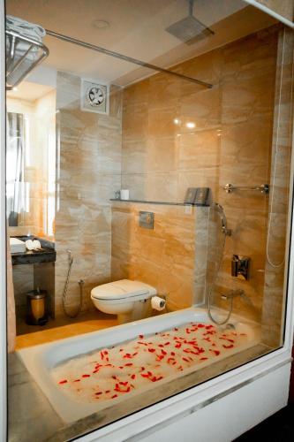 a bathroom with a shower and a tub with a toilet at Himalayan Front Hotel by KGH Group in Pokhara