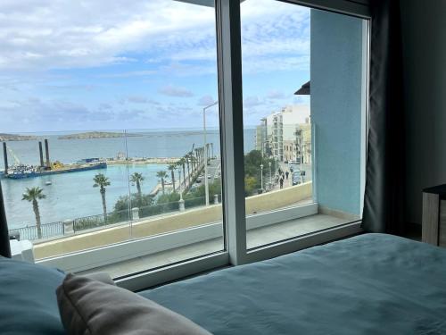 a bedroom with a large window looking out at the ocean at Seafront studio apartment San Paul's Bay in St Paul's Bay