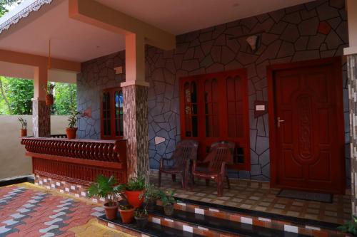 a house with red doors and chairs on a patio at Dean Dale Cottages in Thekkady