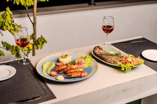a table with two plates of food and two glasses of wine at Mzion Hotel Weligama in Weligama
