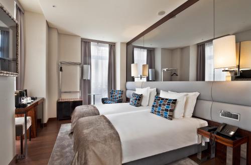 ein Hotelzimmer mit einem großen Bett und einem Schreibtisch in der Unterkunft TURIM Terreiro do Paço Hotel in Lissabon