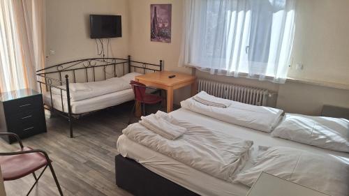 a room with two beds and a table with a table at Pension Alis Augsburg in Augsburg