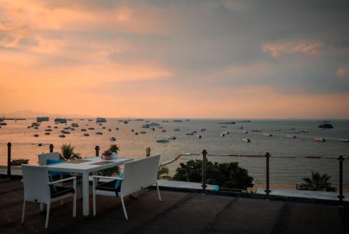 a table and chairs on a balcony with a view of the ocean at Wave Hotel Pattaya in Pattaya Central