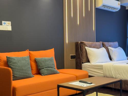 a living room with an orange couch and a table at R&F Princess Cove by Nest Home at Johor Bahru in Johor Bahru