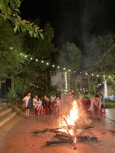 a group of people sitting around a fire at night at Khu Du Lịch Sinh Thái, Nghỉ dưỡng Homestay Hoàng Ánh - Kon Xom Luh in Kon Tum