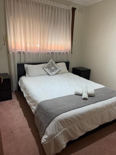 a bedroom with a large white bed with a window at Bundoora cozy room in Melbourne