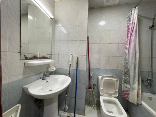 a white bathroom with a sink and a toilet at Reflections Ajman-Home Away Home-Best property for stay in Ajman 