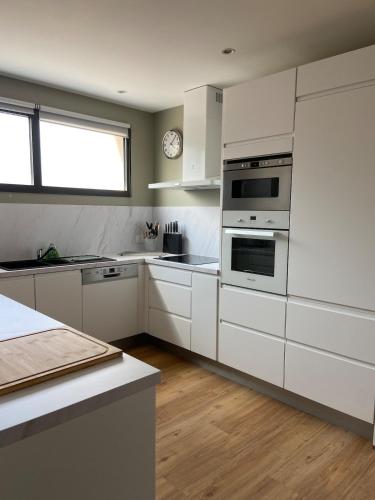 une cuisine avec des placards blancs et une horloge murale dans l'établissement Magnifique appartement à 100 m de la plage, à Agon-Coutainville