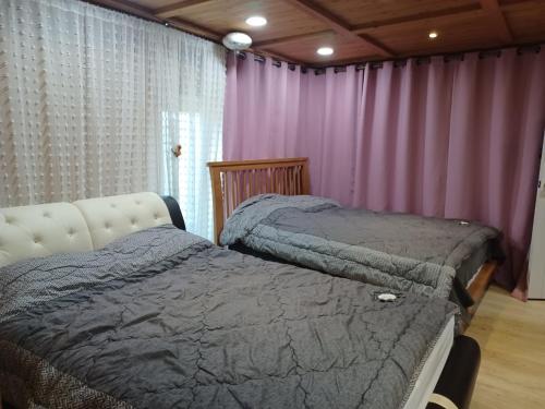 two beds in a bedroom with purple curtains at Vernia in Yeosu