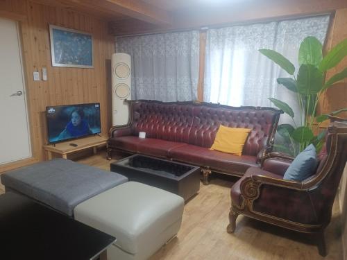 a living room with a leather couch and a tv at Vernia in Yeosu