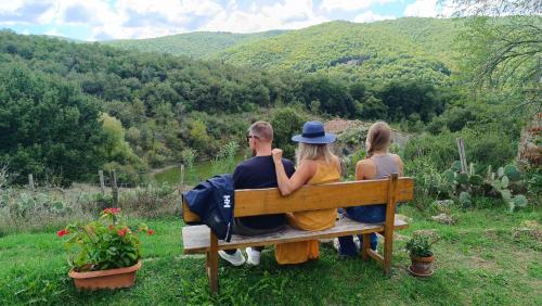 three people sitting on a bench looking at the mountains at Agriturismo Podere Tegline in Radda in Chianti