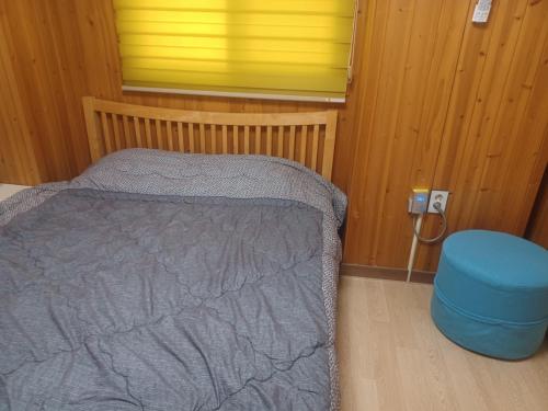 a small bedroom with a bed and a blue stool at Vernia in Yeosu