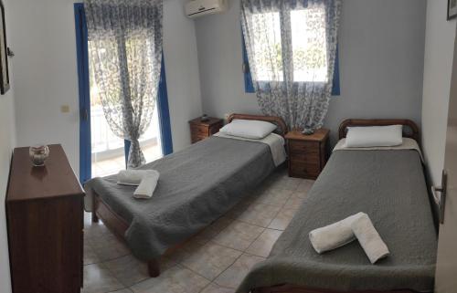 Un dormitorio con dos camas y un escritorio y ventanas. en Villa Amalia, en Vrachonisída touArchangélou
