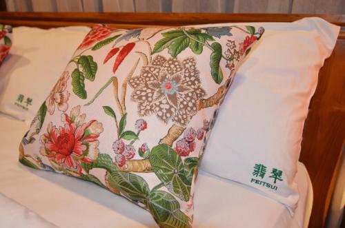 a pillow with a flower pattern on a bed at Feitsui in Chiang Mai