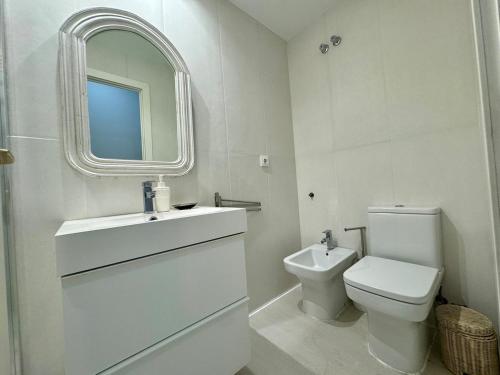 a bathroom with a toilet and a sink and a mirror at R4 Apartment next to Plaza de España and Metro in Seville