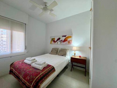 a white bedroom with a bed and a table at R4 Apartment next to Plaza de España and Metro in Seville