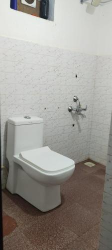 a white toilet in a bathroom with a brick wall at Casa Shanti in Kannur