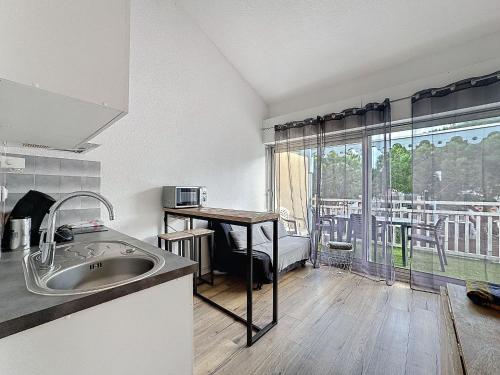 une cuisine avec un évier, une table et une fenêtre dans l'établissement Le Scarlett - Piscine, parking et proche plage, à Palavas-les-Flots