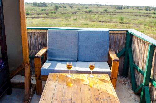 a wooden table with two glasses of wine on a balcony at Amboseli Amanya Lodge in Amboseli