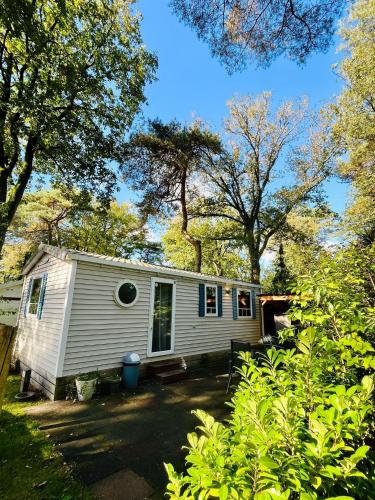 a small white caravan in the middle of trees at Chalet vakantiepark Kleine Belties 18 in Hardenberg
